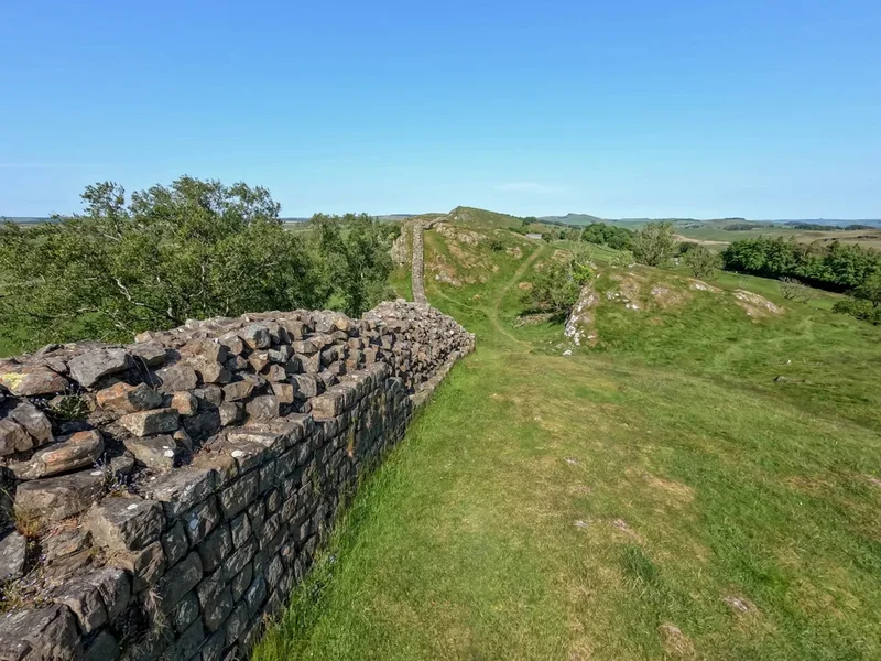 A Stone Wall In The Middle of a Grassy Field